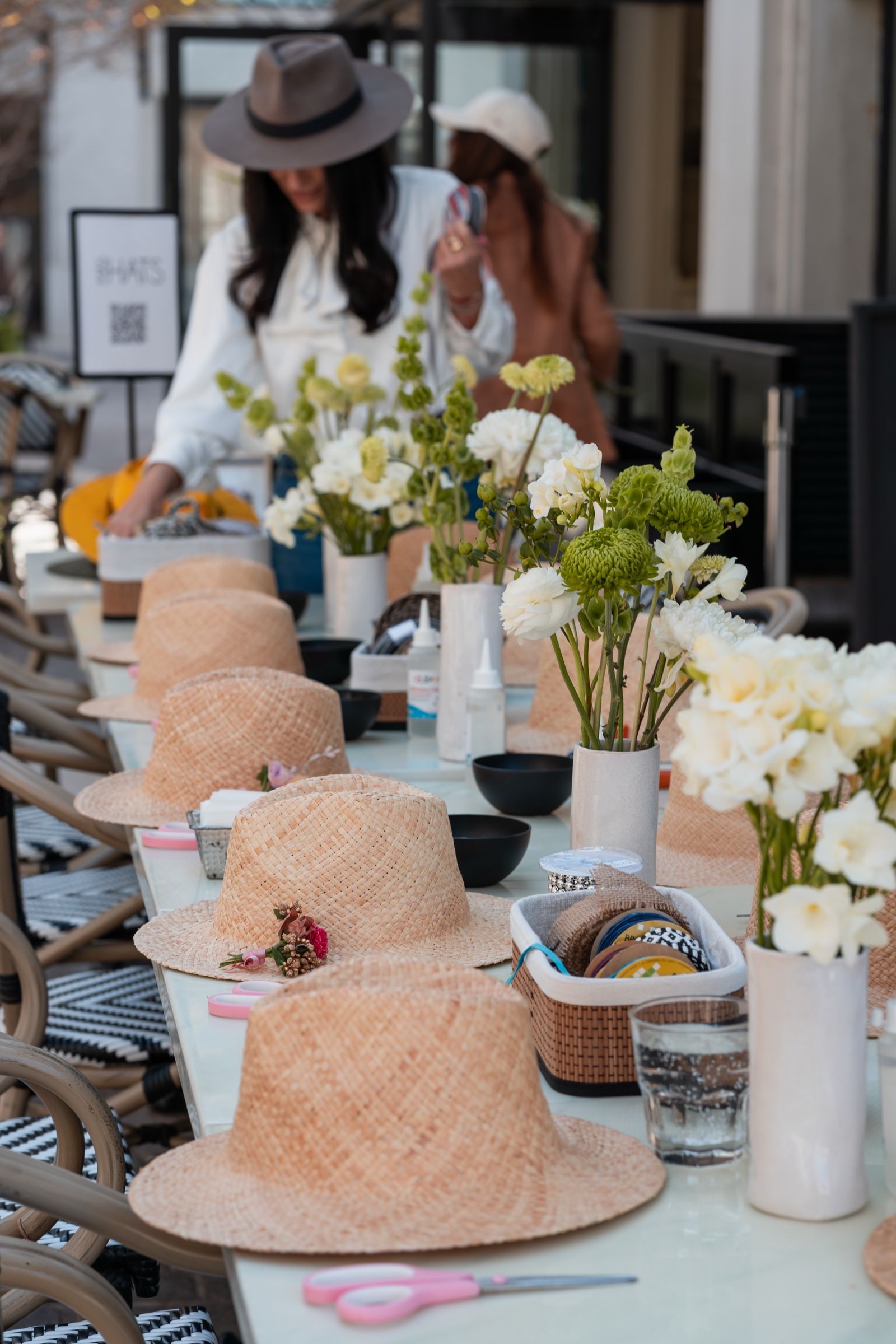 Mesa armada con sombreros de paja, flores blancas y cajas con avíos.